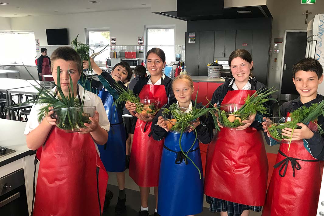 Students display veggies they have harvested, now ready for cooking