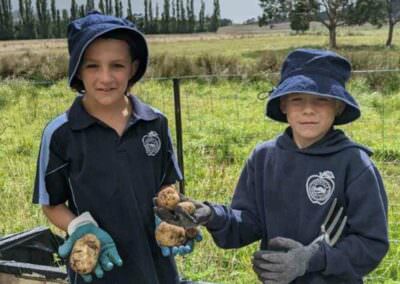Huoville Primary Students holding homegrown potatoes