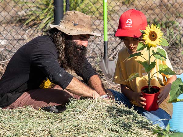 Costa and a student planting a sunflower