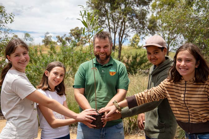 Group of students and teacher holding a seedling