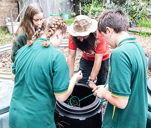 Image Description:  TV personality Costa Georgiadis talking to three primary school students about composting.