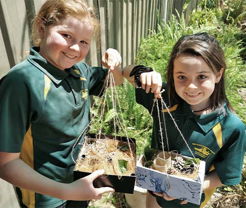 Two students showing their bee hotels